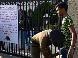 Un policía revisa a un fiel que acude al templo de Santa Teresa en Colombo. AFP/L. Wanniarachchi
