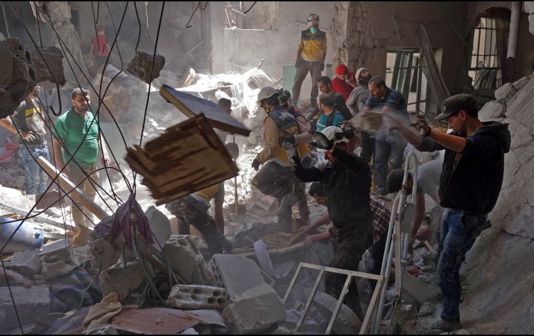 Voluntarios y militares rascatan a personas que quedaron atrapadas en un edificio derrumbado debido a los bombardeos. AFP/M. Haj Kadour