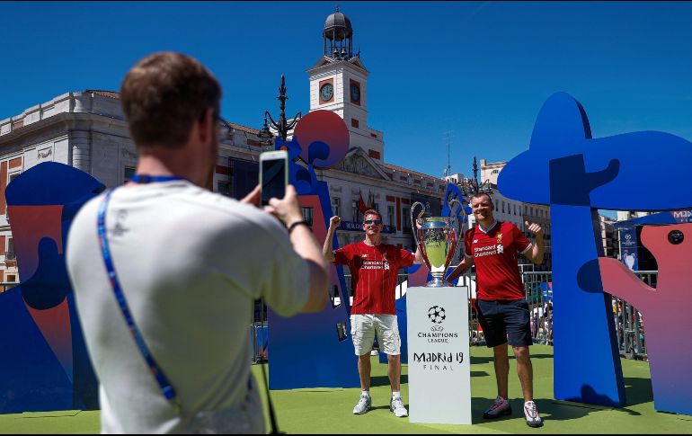 Aficionados del Liverpool posan junto a la “orejona”, que fue exhibida ayer en la Puerta del Sol. EFE/E. Naranjo