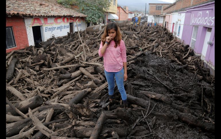 Una joven se ve hoy entre troncos, lodo y escombros arrastrados por un río desbordado en San Gabriel, Jalisco.