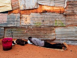 Una persona desplazada de Zimbabwe descansa afuera de una iglesia en el campamento informal de migrantes de Musina, en Sudáfrica. AFP/L. Sola