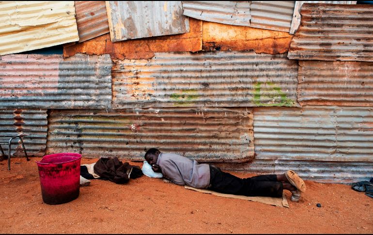 Una persona desplazada de Zimbabwe descansa afuera de una iglesia en el campamento informal de migrantes de Musina, en Sudáfrica. AFP/L. Sola