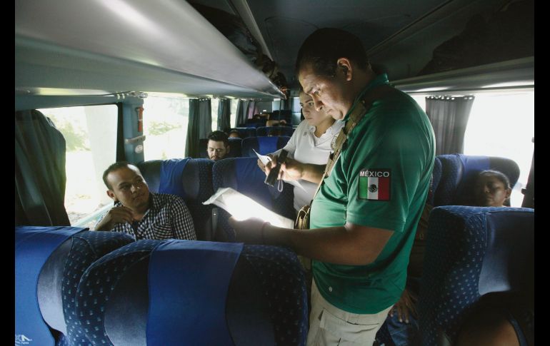 Un agente del INM revisa la situación legal de un extranjero que viajaba en un autobús foráneo en las afueras de Tapachula y que tenía como destino el Norte de México. AFP