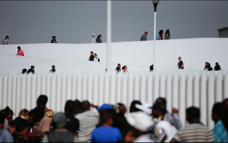 Personas cruzaban ayer (arriba) de Tijuana, Baja California, hacia Estados Unidos, mientras migrantes (abajo) aguardaban para pedir asilo. AP/ARCHIVO
