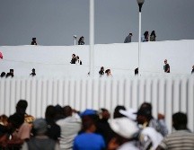 Personas cruzaban ayer (arriba) de Tijuana, Baja California, hacia Estados Unidos, mientras migrantes (abajo) aguardaban para pedir asilo. AP/ARCHIVO
