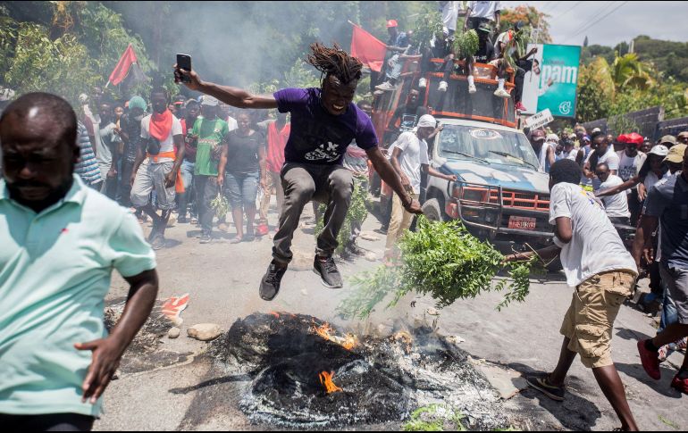 Un hombre salta por encima de un neumático en llamas, este domingo, durante una manifestación para exigir la dimisión del presidente haitiano, en Puerto Príncipe. EFE/J. Herve
