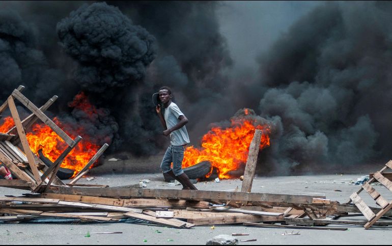 Un hombre pasa frente a una barricada en llamas este lunes, en Puerto Príncipe. EFE/J. Herve