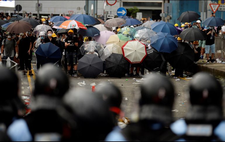 Decenas de protestantes con paraguas encaran a la policía, este miércoles en Hong Kong. EFE/V. Yuen