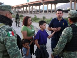 Policías federales intentan persuadir a una familia migrante para que no cruce el Río Bravo debajo del puente internacional fronterizo hacia EU. EFE/D. Peinado