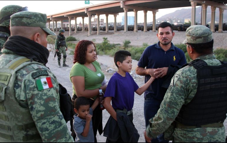 Policías federales intentan persuadir a una familia migrante para que no cruce el Río Bravo debajo del puente internacional fronterizo hacia EU. EFE/D. Peinado