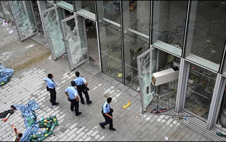 Policías vigilan hoy afuera del recinto legislativo en Hong Kong, que presenta daños tras las protestas de la víspera. AFP/H. Retamal