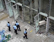 Policías vigilan hoy afuera del recinto legislativo en Hong Kong, que presenta daños tras las protestas de la víspera. AFP/H. Retamal