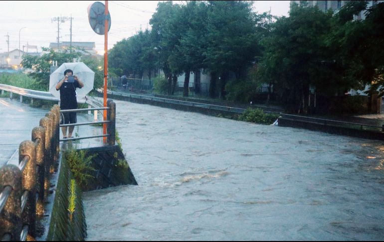 Un hombre capta el crecido río Wada en Kagoshima, en la isla de Kyushu. AFP/JIJI PRESS