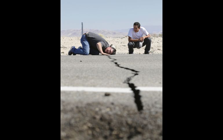 Un ciudadano baja la cabeza para observar a detalle una grieta causada por el terremoto a las afueras de Ridgecrest, California. AP