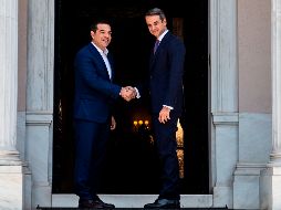 Kyriakos Mitsotakis (d) y  Alexis Tsipras se saludan en el palacio Maximus en Atenas. AFP/A. Tzortzinis
