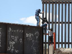 Un grupo de personas tratan de saltar el muro para entrar a territorio estadounidense, desde el puente negro, en la línea fronteriza de Ciudad Juárez. EFE / D. Peinado