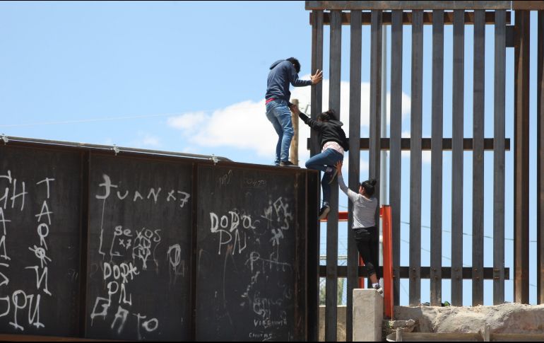 Un grupo de personas tratan de saltar el muro para entrar a territorio estadounidense, desde el puente negro, en la línea fronteriza de Ciudad Juárez. EFE / D. Peinado