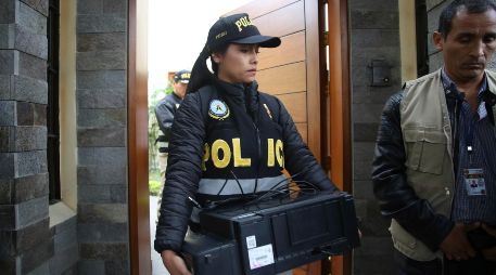 Una oficial de policía sale de la casa del expresidente Humala con un escáner recogido como posible prueba. AP/M. Mejía
