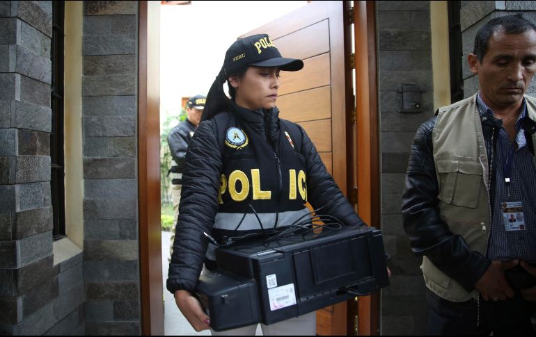 Una oficial de policía sale de la casa del expresidente Humala con un escáner recogido como posible prueba. AP/M. Mejía
