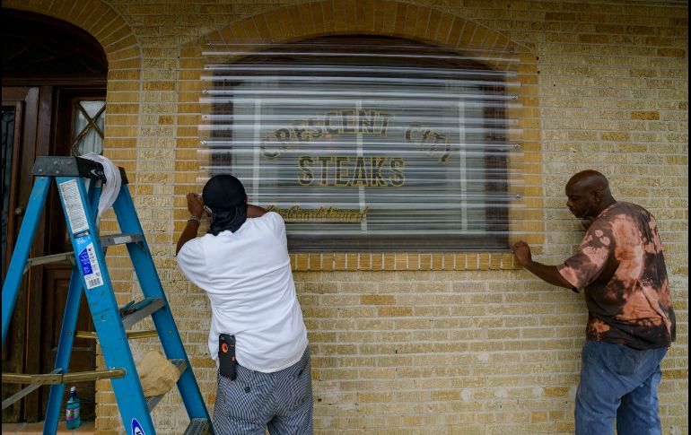 Trabajadores colocan protectores sobre las ventanas de un negocio este viernes en Nueva Orleans.