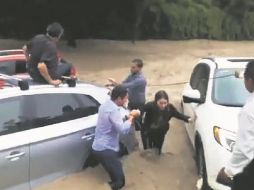 Personas auxiliaron a una joven que quedó atrapada dentro de su vehículo (color rojo) luego del desbordamiento del canal de avenida Patria. ESPECIAL/Canal 10 Quiero TV