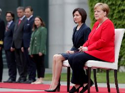 Angela Merkel (d) y la primera ministra moldava Maia Sandu mientras sonaban los himnos de cada país en la ceremonia en Berlín. AP/M. Sohn