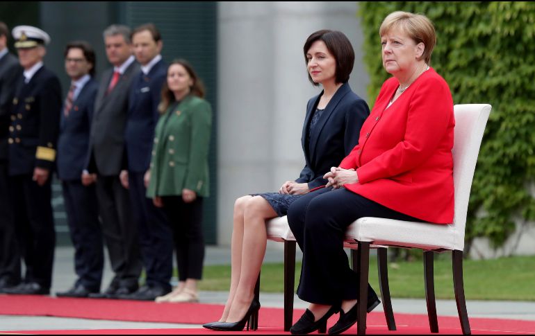Angela Merkel (d) y la primera ministra moldava Maia Sandu mientras sonaban los himnos de cada país en la ceremonia en Berlín. AP/M. Sohn