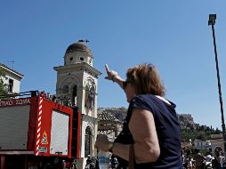La cruz de una de las iglesias de Atenas, localizada en la cúpula del edificio, se partió debido a la fuerza del sismo; una mujer señala el daño. EFE/K. Tsironis