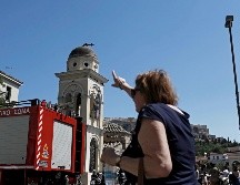 La cruz de una de las iglesias de Atenas, localizada en la cúpula del edificio, se partió debido a la fuerza del sismo; una mujer señala el daño. EFE/K. Tsironis