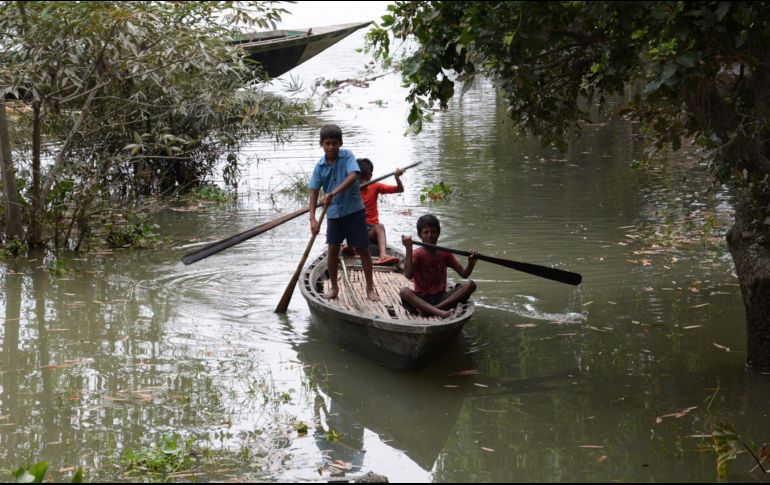 Niños usan un bote rudimentario para transportarse en medio de las calles cubiertas de agua, en Assam, India. EFE