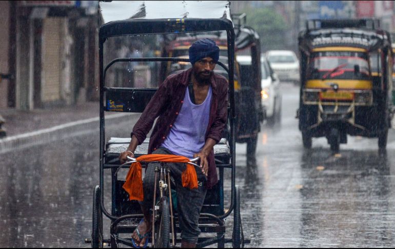 Un hombre conduce su bicicleta en medio de una fuerte lluvia en la India. AFP / N. Nanu
