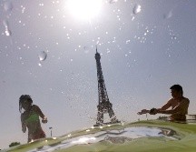 Personas se meten este jueves a las fuentes junto a la torre Eiffel en París. AFP/D. Faget