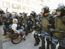 Un persona en silla de ruedas se abre paso entre la ola de antimotines, en la capital rusa. EFE