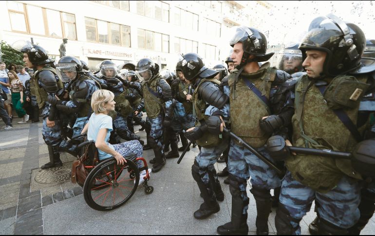 Un persona en silla de ruedas se abre paso entre la ola de antimotines, en la capital rusa. EFE