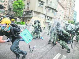Manifestantes huyen de los granaderos en el Distrito Yuen Long. AP