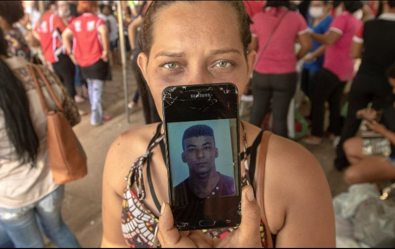 Una mujer muestra una fotografía mientras espera junto a otras personas la entrega de los cuerpos de las víctimas de la masacre en el Centro de Recuperación Regional de Altamira. EFE / J. Alves