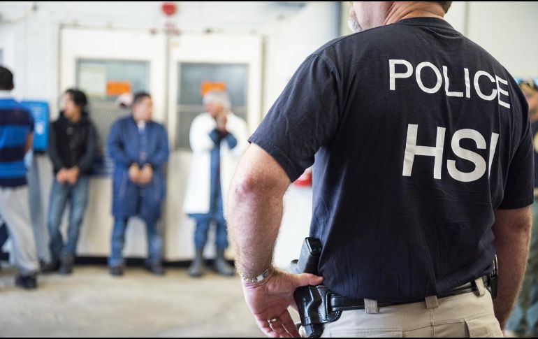 Un agente vigila a inmigrantes detenidos ayer durante una redada en Mississippi.  AFP/ICE