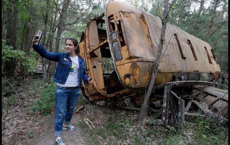 na joven se toma una selfie junto a un autobús abandonado, durante una visita a Chernóbil en junio pasado. EFE/ARCHIVO