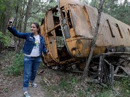 na joven se toma una selfie junto a un autobús abandonado, durante una visita a Chernóbil. EFE/ARCHIVO