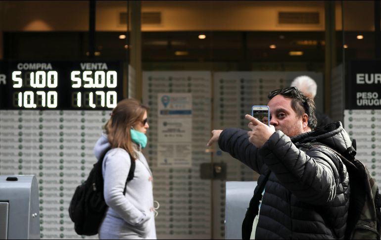 Un hombre se fotografía delante de una casa de cambio donde se anuncia el elevado precio del dólar. AP/N. Pisarenko