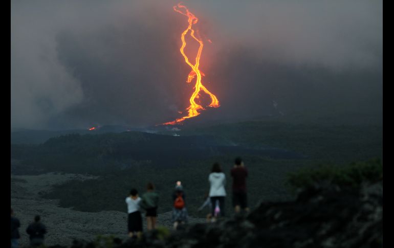 Personas observan la lava que baja del volcán. AFP/R. Bouhet