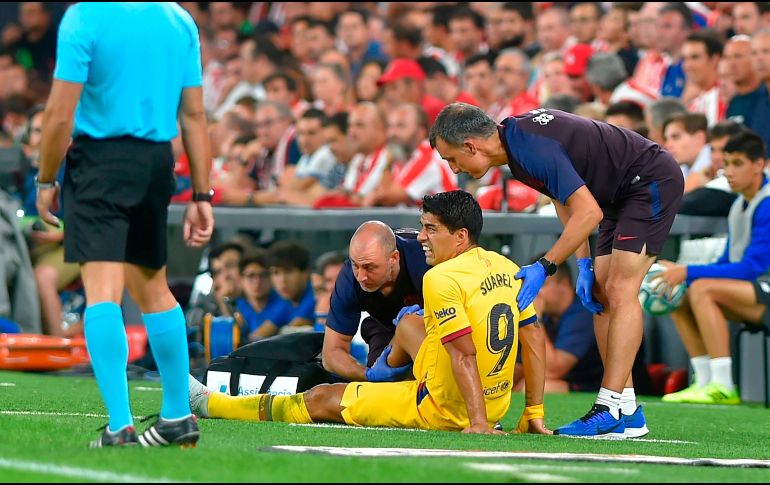 Personal médico atiende al uruguayo Luis Suárez, quien fue suplido al minuto 39 por Rafinha. AFP/A. Gillenea