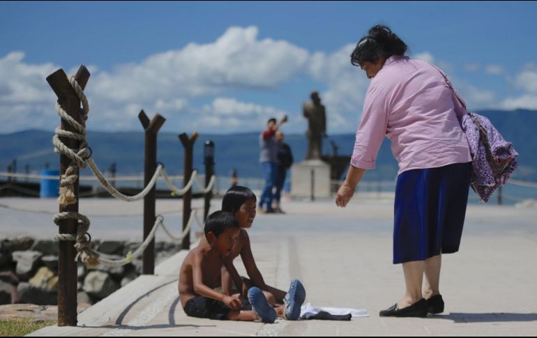 Una mujer se detiene para dar una moneda a los niños en el andador de Chapala. EL INFORMADOR/F. Atilano