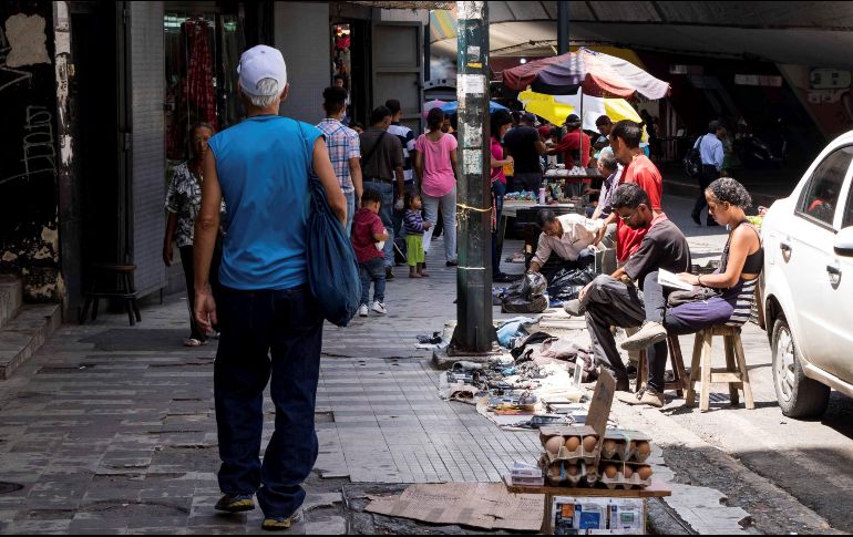 Un hombre camina frente a puestos de venta ambulantes en Caracas; el país suma seis años de recesión y sin señales de cambio o mejora inmediata en el horizonte. EFE/M. Angarita