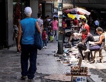 Un hombre camina frente a puestos de venta ambulantes en Caracas; el país suma seis años de recesión y sin señales de cambio o mejora inmediata en el horizonte. EFE/M. Angarita