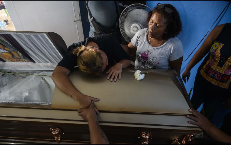Vanessa Blas llora en el ataúd de su esposo, Erick Hernández, el DJ del bar “El Caballo Blanco”. AFP / P. Pardo