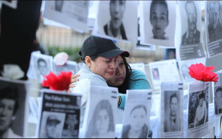 Dos mujeres observan fotografías de personas desaparecidas este viernes, en las afueras del Palacio Nacional, en la Ciudad de México. EFE/M. Guzmán