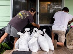 Dos personas colocan sacos de arena en la entrada de una vivienda ante la cercanía del huracán. AP/S. Morton