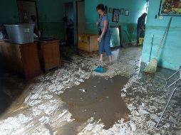 Una mujer saca el lodo de su vivienda luego de la tormenta 