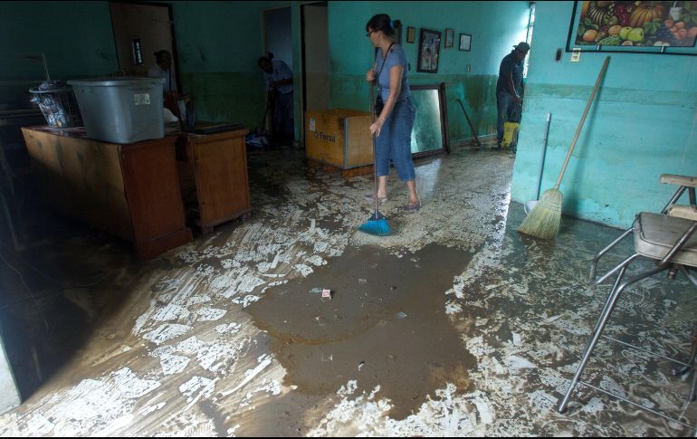 Una mujer saca el lodo de su vivienda luego de la tormenta 